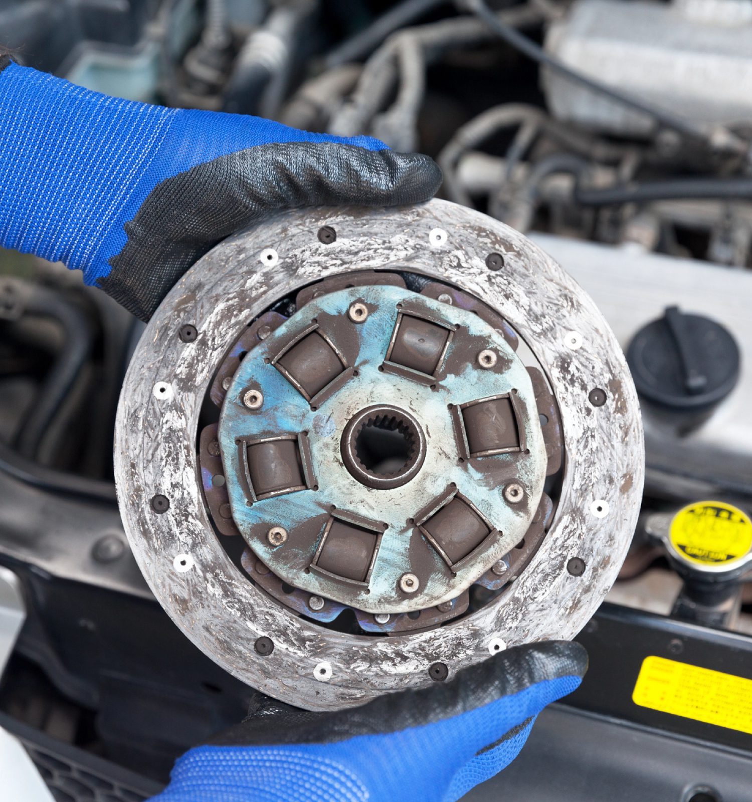 mechanic holding a worn out vehicle clutch - ADL Auto Repair & Driveshafts