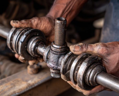 mechanic holding a worn out driveshaft - ADL Auto Repair & Driveshafts Driveshaft Maintenance Schedule