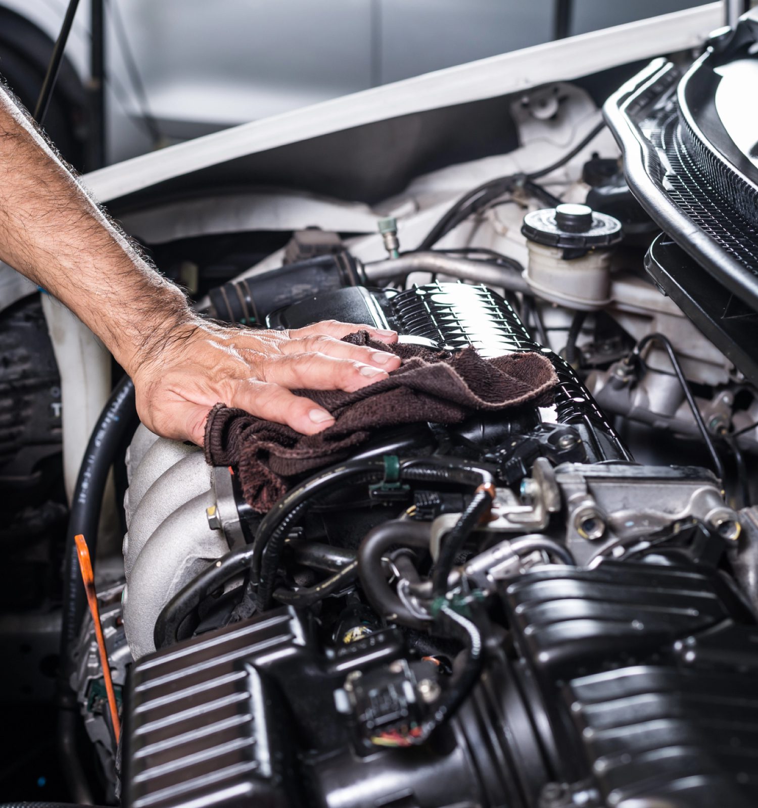 mechanic cleaning the engine bay with a rag - ADL Auto Repair & Driveshafts