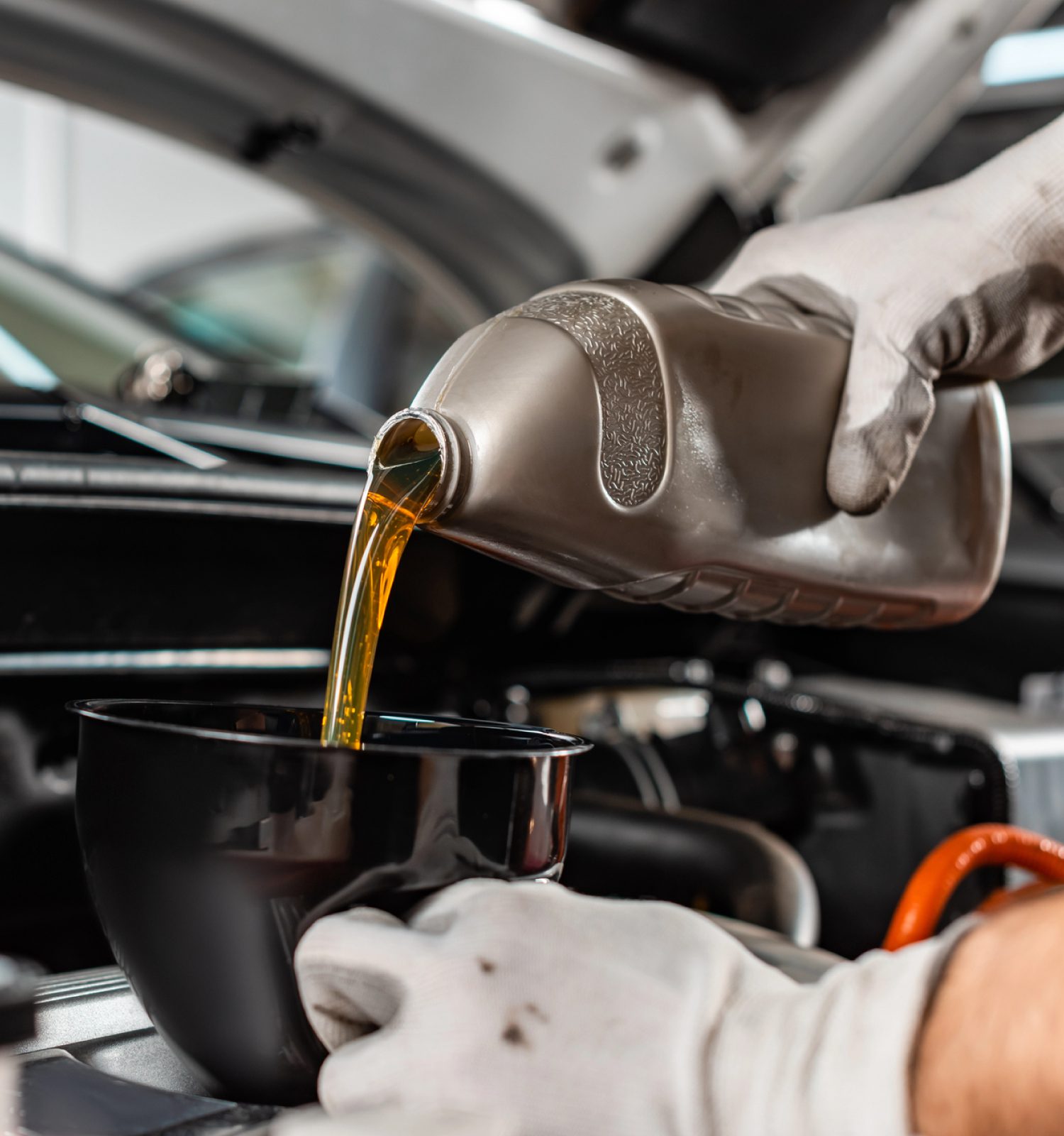 mechanic adding oil to a vehicle using a funnel - ADL Auto Repair & Driveshafts