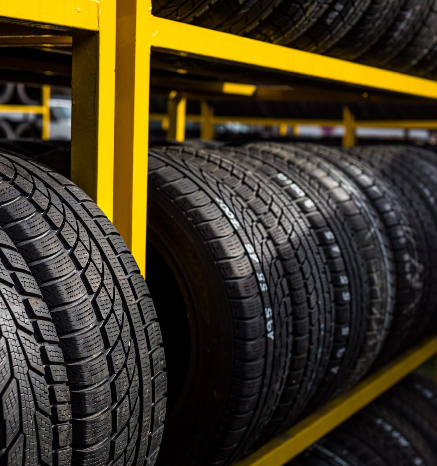 multiple tires on a yellow shelf - ADL Auto Repair & Driveshafts