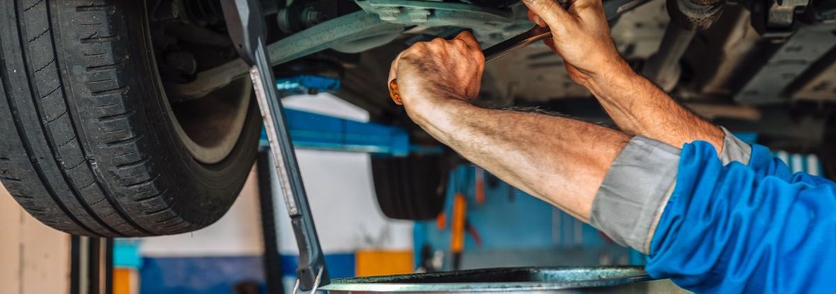 mechanic under a vehicle performing an oil change - ADL Auto Repair & Driveshafts oil change