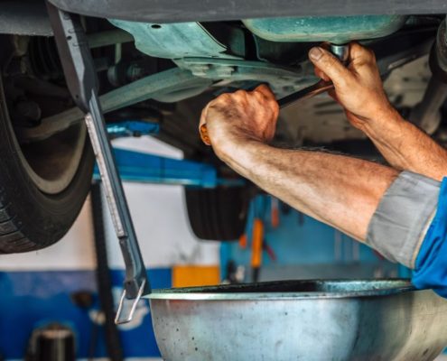 mechanic under a vehicle performing an oil change - ADL Auto Repair & Driveshafts oil change