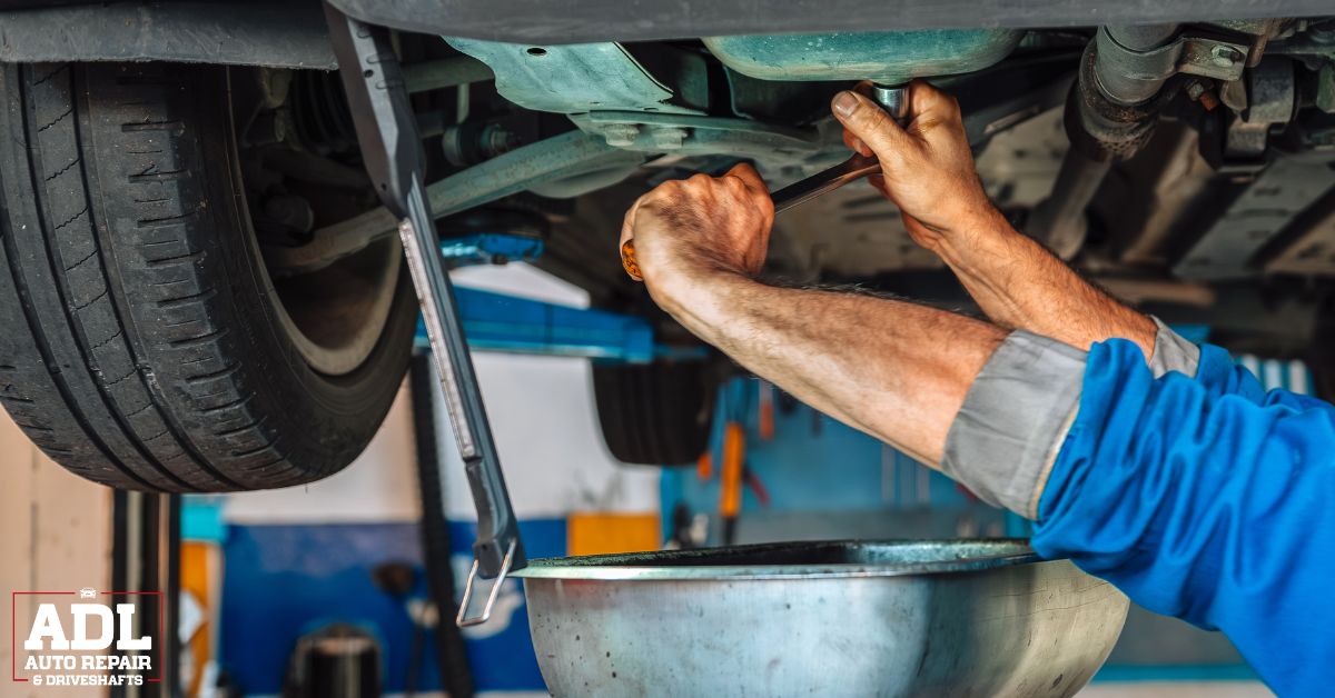 mechanic under a vehicle performing an oil change - ADL Auto Repair & Driveshafts Fleet maintenance Centerville MN