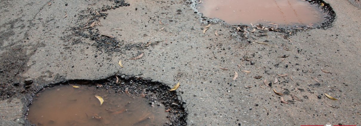 road with pot holes filled with water - ADL Auto Repair Driveshafts suspension repair
