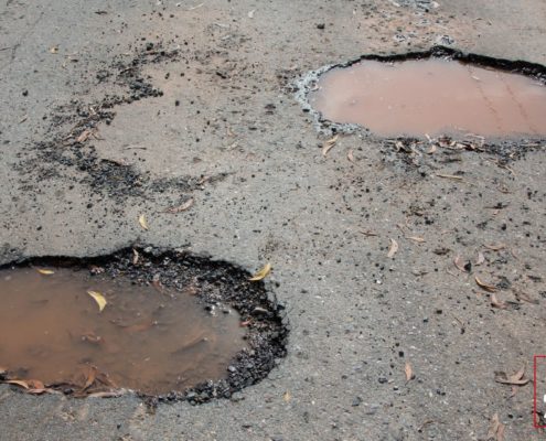 road with pot holes filled with water - ADL Auto Repair Driveshafts suspension repair