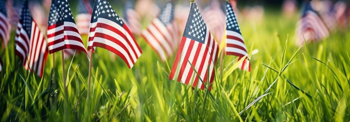 close up of American flags in green grass - ADL Auto Repair & Driveshafts Memorial Day Road Trip Prep