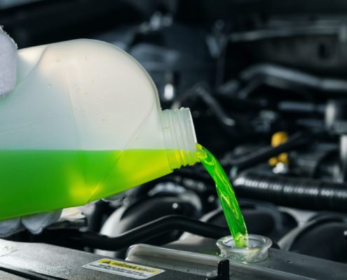 mechanic adding bright green coolant fluid to a vehicle - ADL Auto Repair & Driveshafts