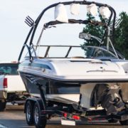 ADLAutoRepairandDriveshafts-why-does-my-truck-vibrate-when-towing-a-boat-camper-1 White truck towing a speed boat down a road - ADL Auto Repair & Driveshafts why does my truck vibrate when towing a boat or camper